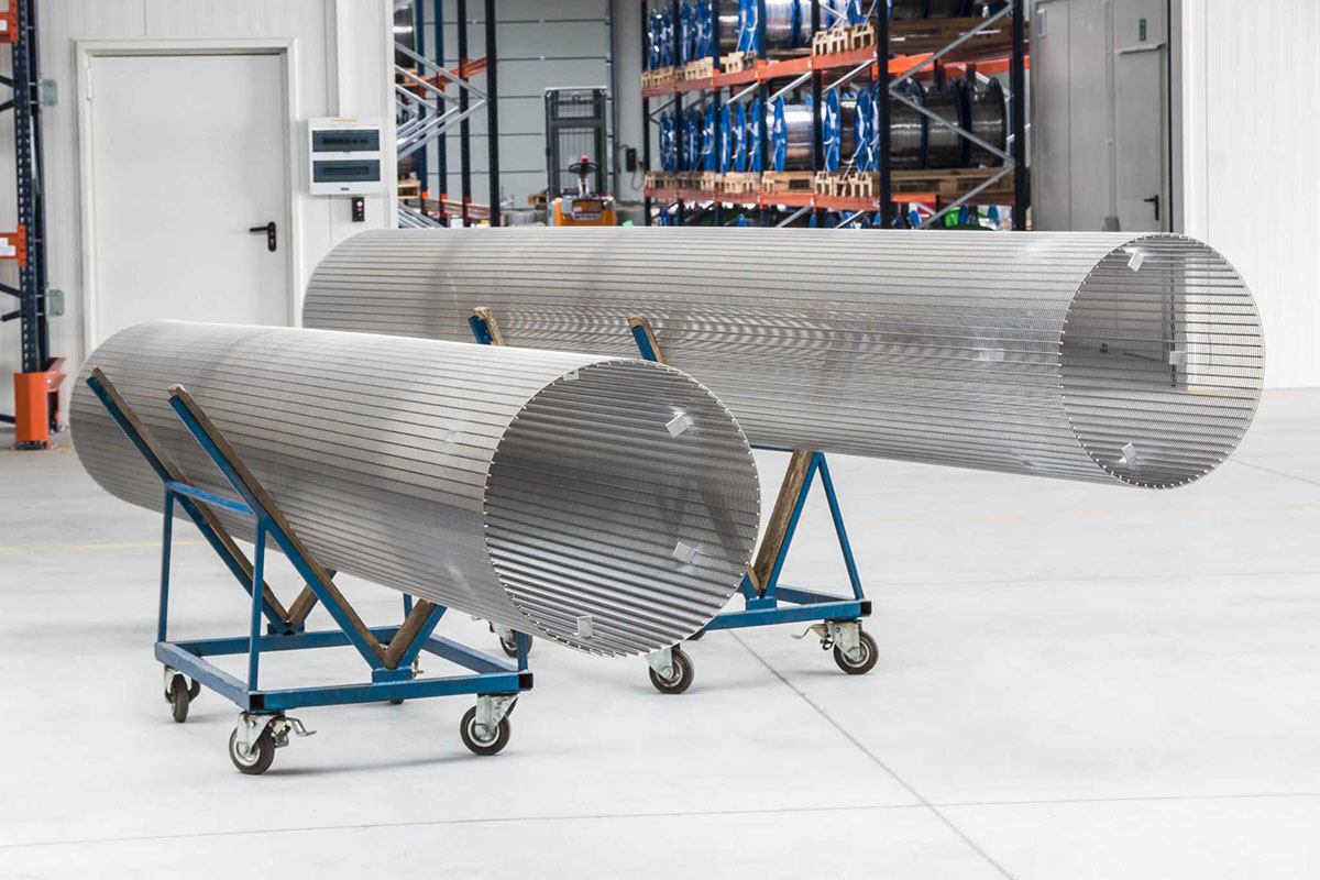 Two stainless steel wedge wire cylinders on wheeled supports in a workshop